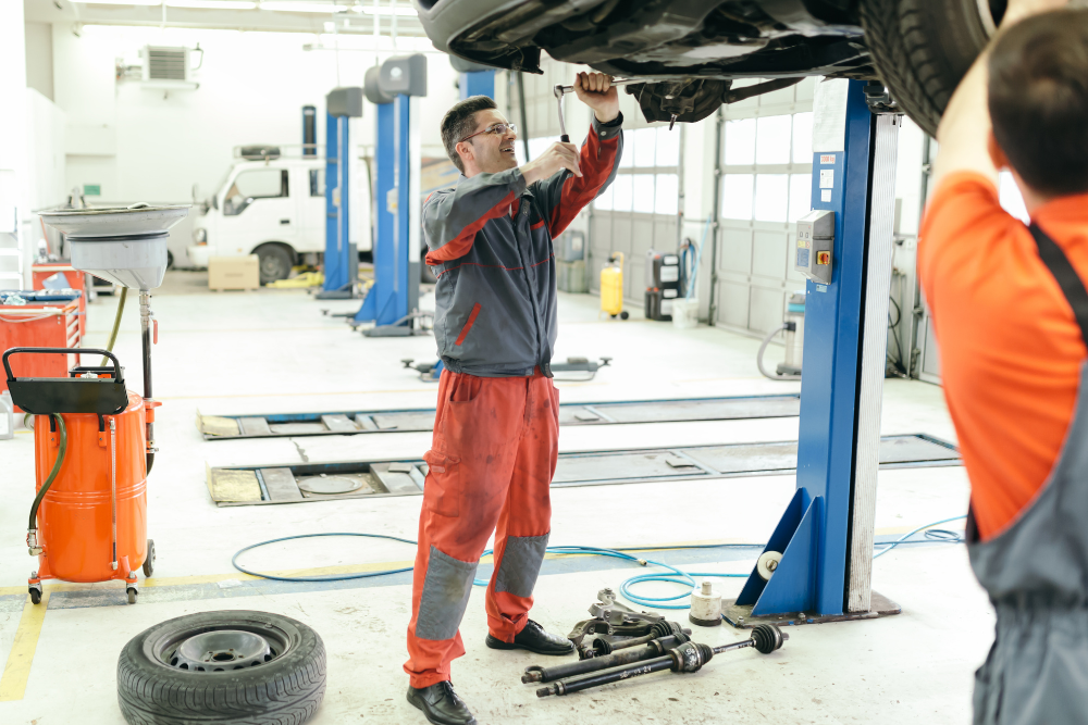 Man using a tablet next to a car he is working on
